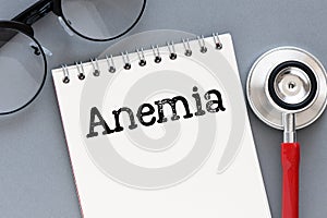 The word ANEMIA written in a notebook on a gray background next to a stethoscope