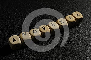 Word Anorexia made of wooden cubes on black background, closeup
