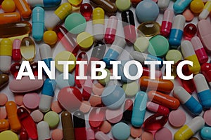Word Antibiotic and lots of different colorful pills as background, top view
