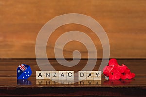 Word Anzac day on wood block with red flower on vintage wood