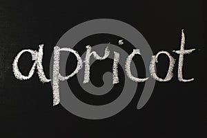 Word apricot written in white chalk on a black chalkboard