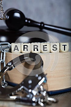 Word ARREST composed of wooden letters.