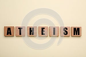 Word Atheism made of wooden squares with letters on beige background, top view