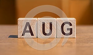 Word AUG on wooden cubes over orange wall background