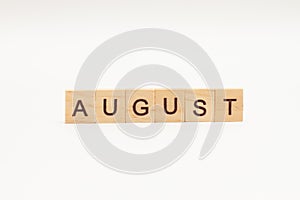 Word AUGUST made of wooden blocks on white background. Month of year. The end of the summer