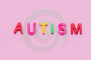 Word AUTISM on pink background, top view