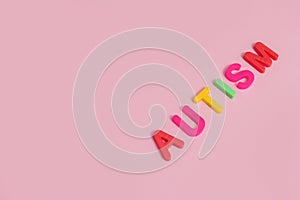 Word AUTISM on pink background, top view