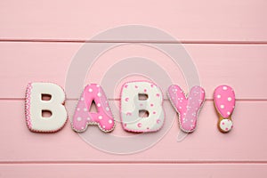 Word BABY made of tasty cookies on pink wooden table, flat lay