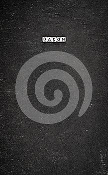 Word bacon on black stone background
