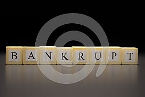 The word BANKRUPT written on wooden cubes isolated on a black background