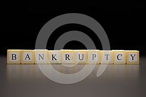 The word BANKRUPTCY written on wooden cubes isolated on a black background