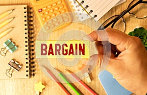 The word BARGAIN made from wooden cubes on blue background. Conceptual photo