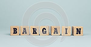 The word BARGAIN made from wooden cubes on blue background