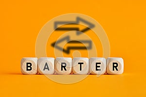 The word barter written on wooden cubes with exchange icons on yellow background. Trade in business market