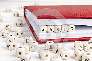 Word Basic written in wooden blocks in notebook on wooden table.