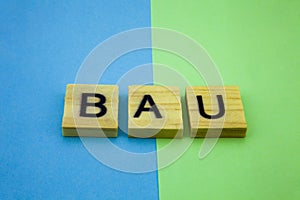 Word BAU on the green and blue background. Business As Usual concept image.
