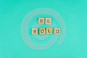 Word be bold. The phrase is laid out in wooden letters. Top view. Motivation. Blue background. Copy space