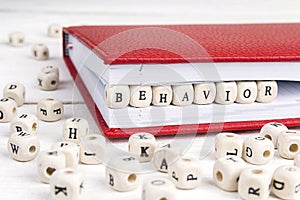 Word Behavior written in wooden blocks in notebook on white wood