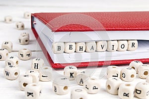 Word Behavior written in wooden blocks in notebook on white wood photo