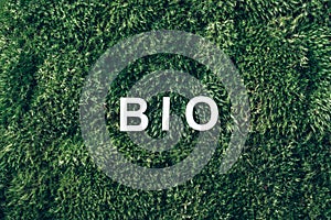 Word Bio on moss, green grass background. Top view. Copy space. Banner. Biophilia concept. Nature backdrop