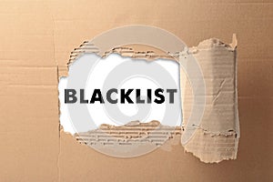 Word Blacklist on white paper, view through hole in cardboard