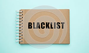 Word Blacklist written in notepad on light blue background, top view