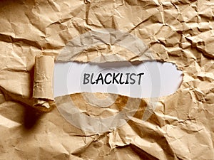 The word blacklist written under a brown torn paper