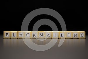 The word BLACKMAILING written on wooden cubes isolated on a black background