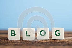 Word BLOG on wooden table with blue background copy space. Blogging communication content, social media networking and commercial