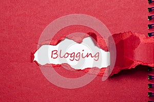 The word blogging appearing behind torn paper