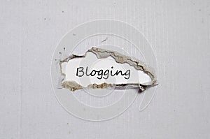 The word blogging appearing behind torn paper