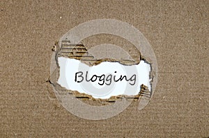 The word blogging appearing behind torn paper