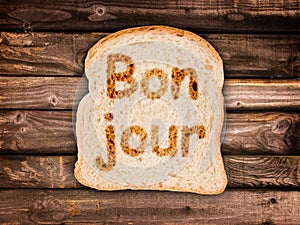 Word bonjour written on a toasted slice of bread