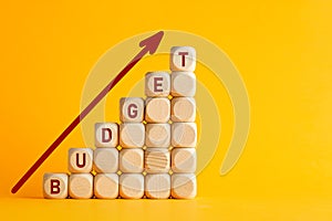 The word budget on wooden cubes against yellow background. Financial budget or investment increase or growth in business