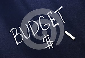 The word budget is written in white chalk on a black surface and a dollar sign