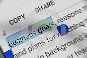 Word `business goals` selected and highlighted digitally on mobile display screen