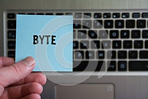 Word BYTE on sticky note hold in hand on keyboard background