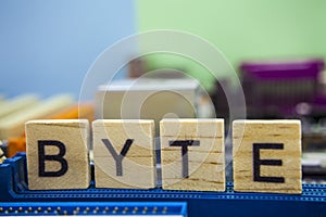 Word BYTE on the wooden blocks with computers mainboard background. Information technology background with mainboard.