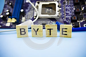 Word BYTE on the wooden blocks with computers mainboard background. Information technology background with mainboard.