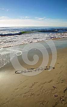 The word California written in sand on the beach.