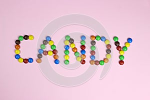 The word candy are contained by colored candies on a pink background
