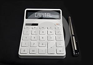 Word capital on calculator over black background