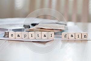 Word CAPITAL GAIN composed of wooden letters.