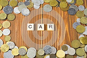 Word CAR on wooden cube with coins frame at wood background. Finance concept.