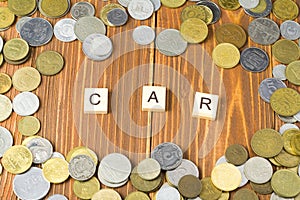 Word CAR on wooden cube with coins frame at wood background. Finance concept.