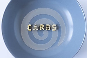 The word `carbs` made with pasta letters