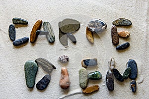 Word: CARPE DIEM, written using colored stones on white sand