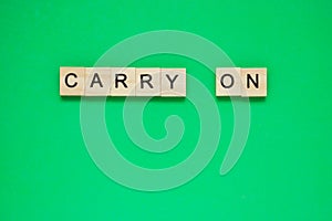 Word carry on. Top view of wooden blocks with letters on green surface