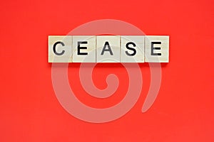 Word cease. Top view of wooden blocks with letters on red surface