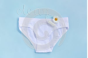 Word CLEAN from white thread hygienic female tampon, chamomile flower and women`s panties on blue background. Concept hygiene